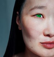 Asian woman face. Half face photo. Hazel color eyes and moles.  Asian eyes. Female looking away. Monolid eyes. Vertical photo.